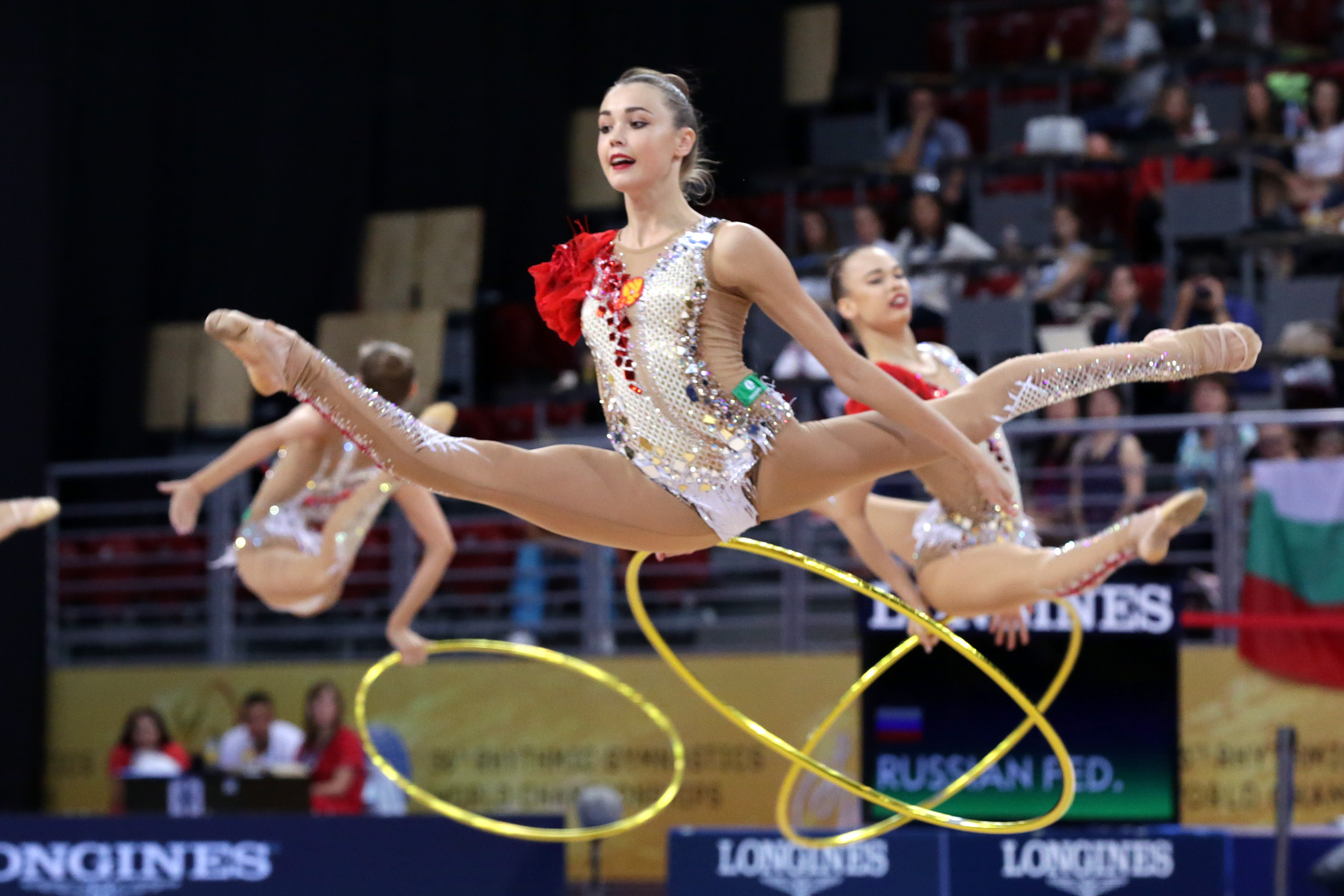 A rhythmic gymnast performing with a ribbon, showcasing flexibility, balance, and grace in a competition.